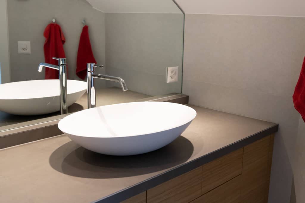 Lavabo blanc sur meuble dans salle de bains rénovée à Lutry