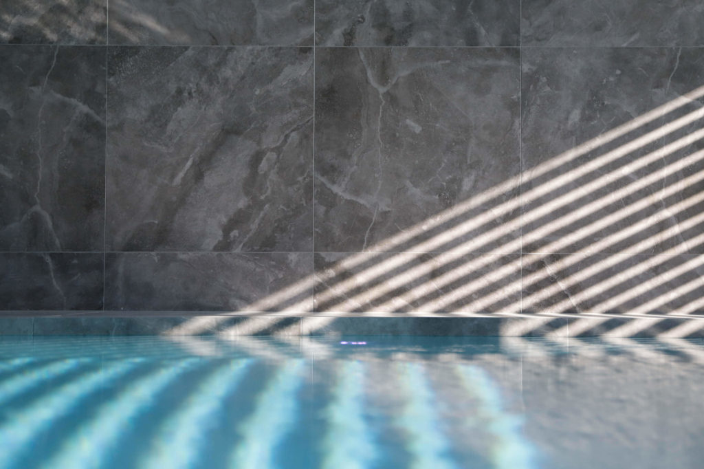 Carrelage grand format imitation pierre foncé dans piscine intérieure