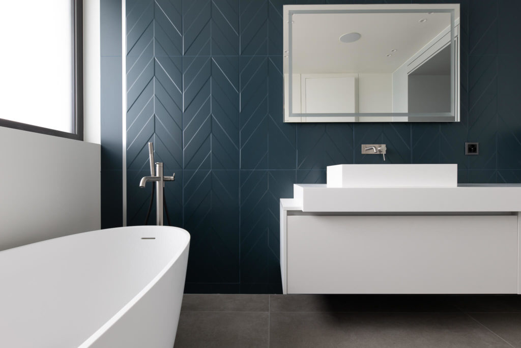 Rénovation d'une salle de bains avec carrelage en chevron bleu et mobilier de salle de bain bleu.