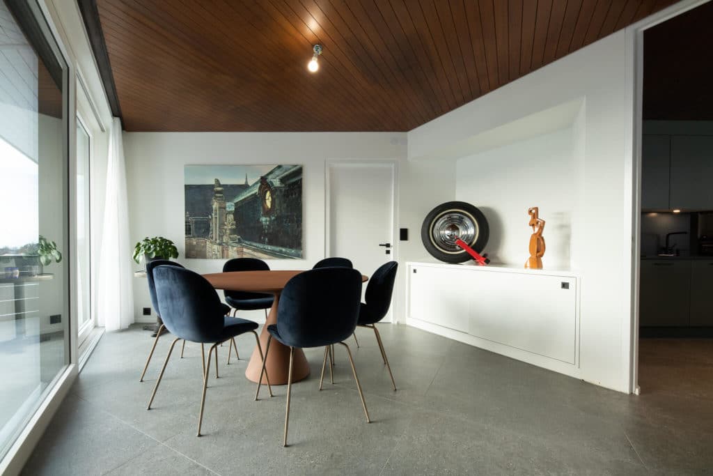 Salle à manger dans une rénovation de maison à Montreux. Mobilier design. Carrelage gris et murs blancs.