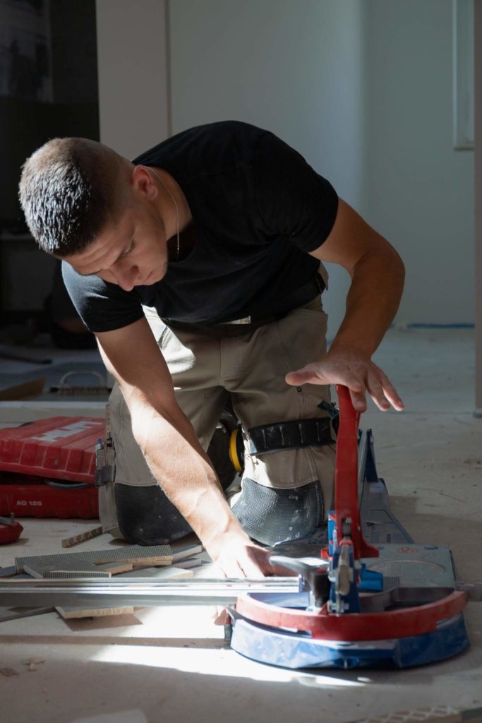 Employé qui coupe avec précision et rapidité un carrelage avec un machine