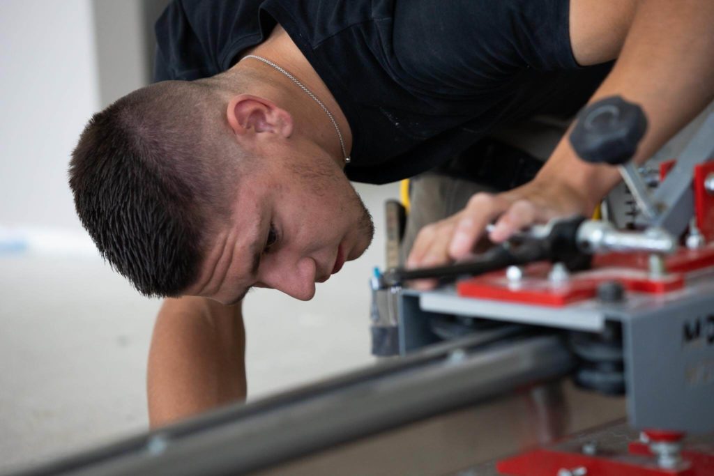 Apprenti découpant du carrelage avec une machine pour couper le plein format