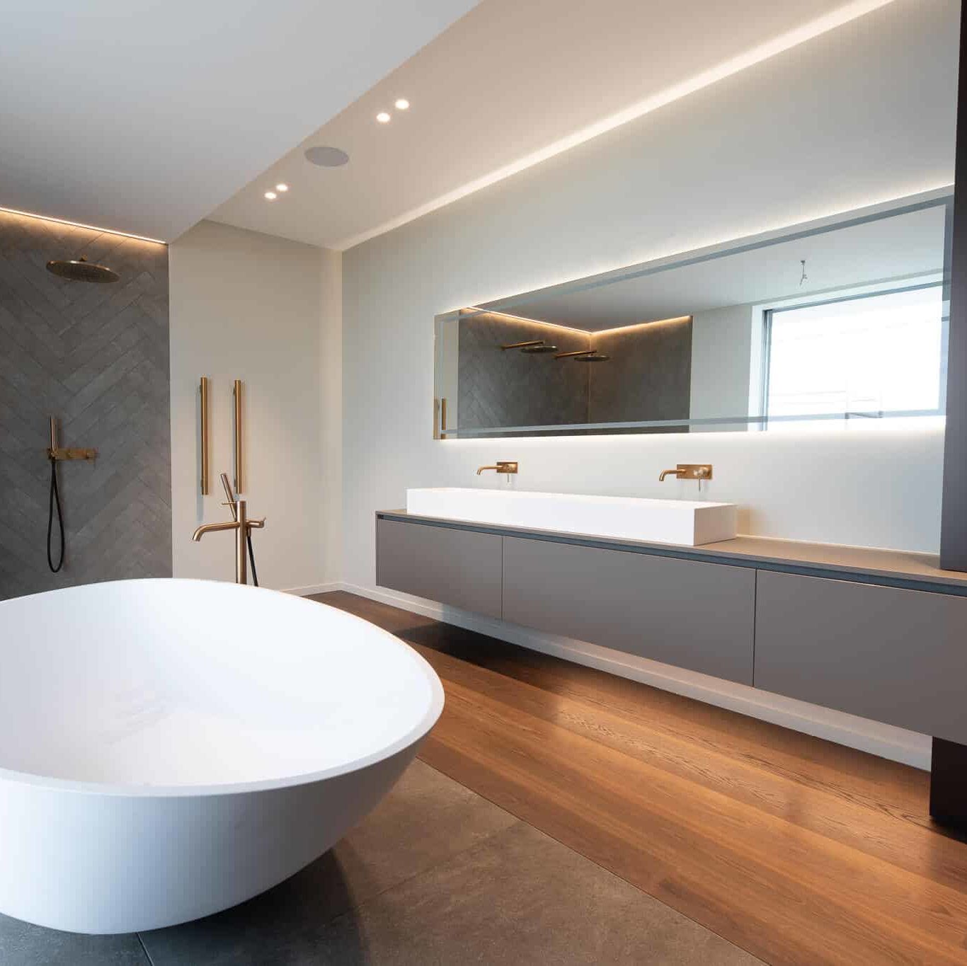 Salle de bains moderne avec parquet et carrelage. Double douche italiennes et grande baignoire blanche.