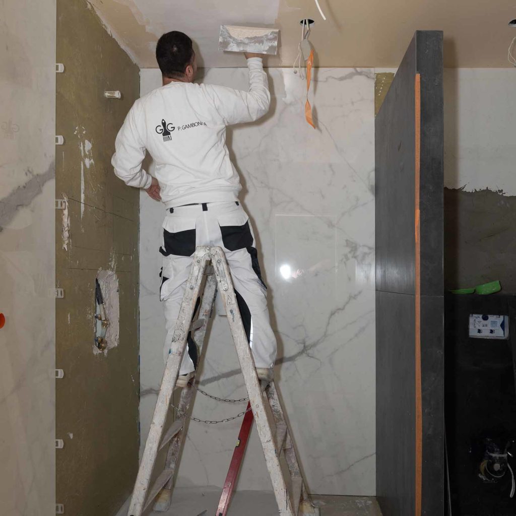 Peintre qui lisse le plafond d'une salle de bains